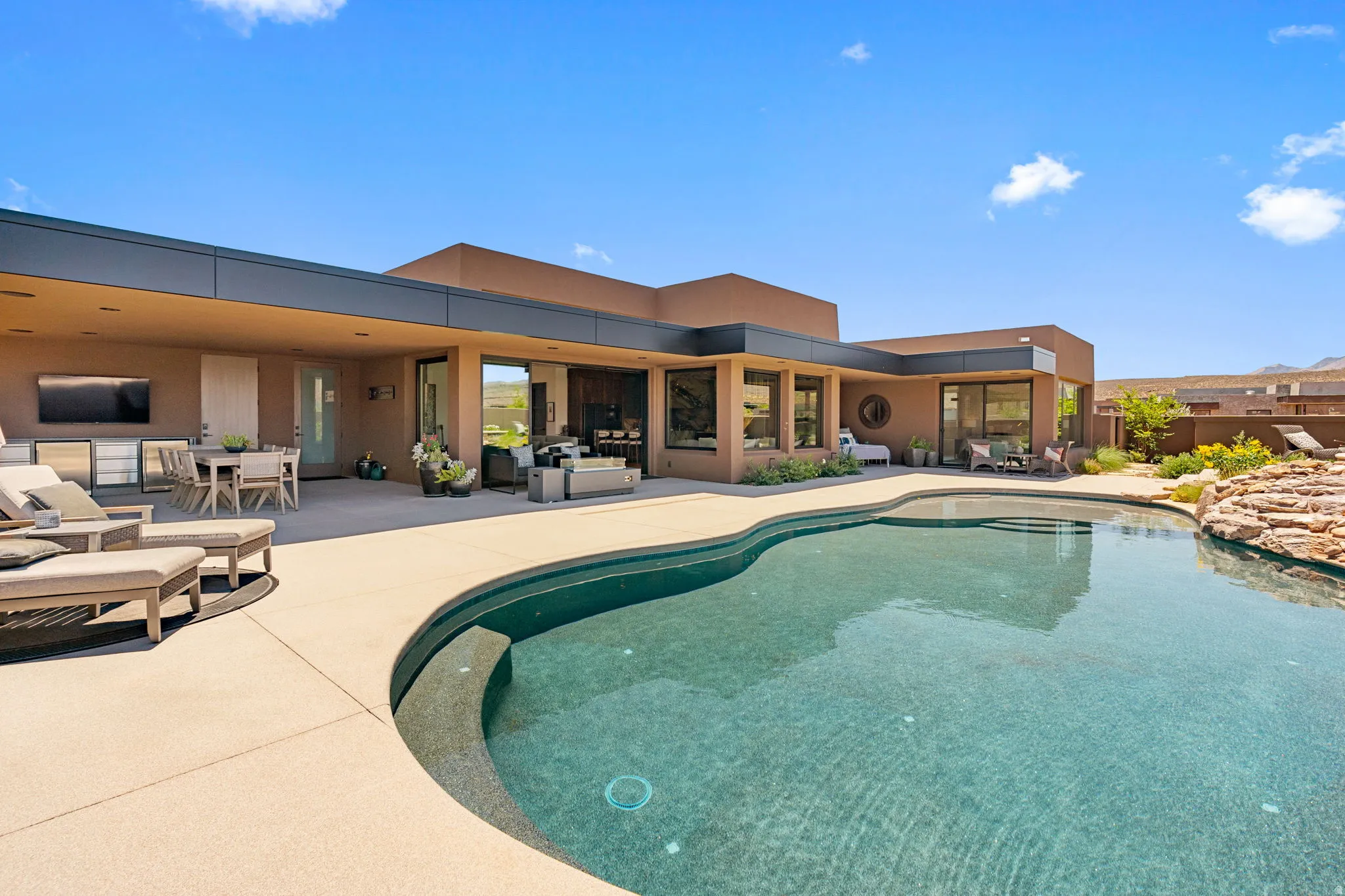 Resort-style backyard featuring a curvilinear swimming pool, an expansive patio, and a built-in outdoor kitchen