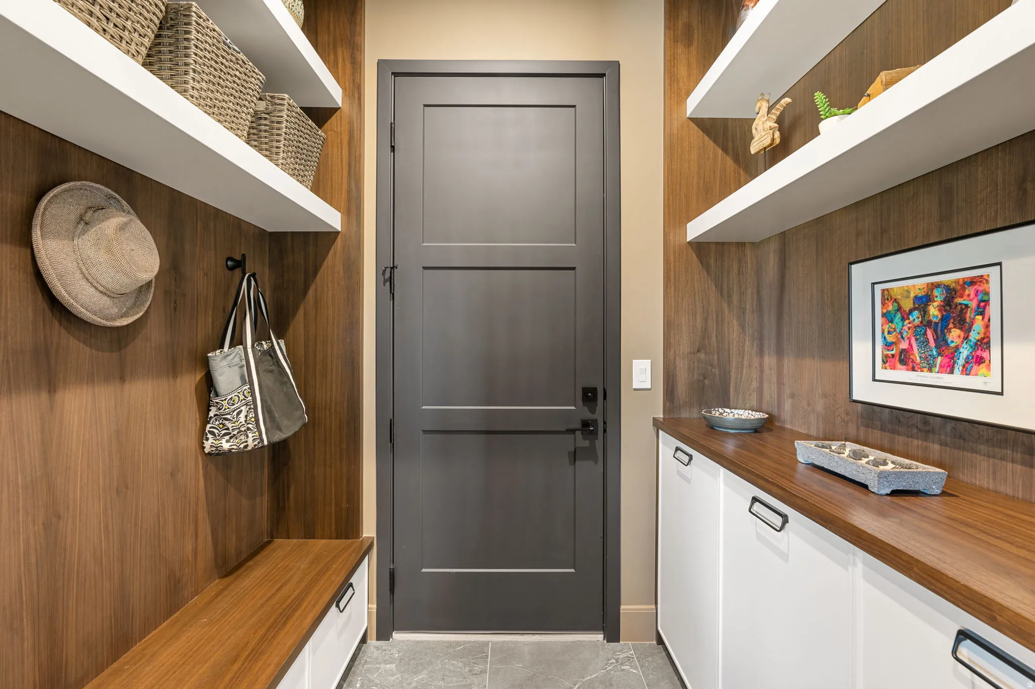 Mudroom featuring custom cabinets, shelves, wall panels, and floor tiles
