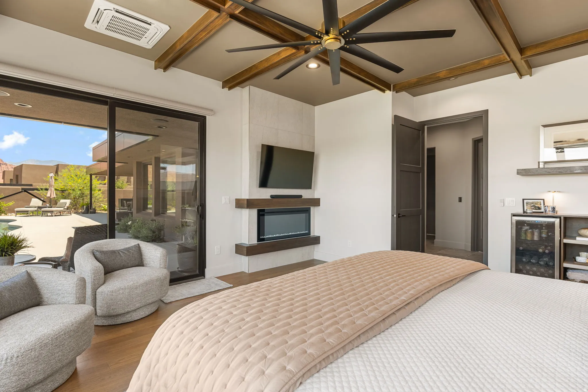 Owner's Suite featuring a ceiling with exposed wood beams, a contemporary ceiling fan, and hardwood flooring