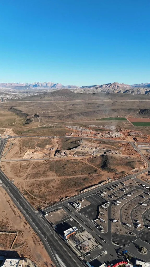 Expansive undeveloped land with visible road infrastructure and distant mountain ranges