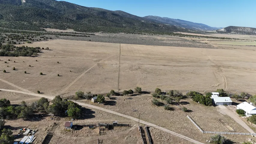 Expansive rural property featuring a vast open field, distant mountains, and scattered natural vegetation