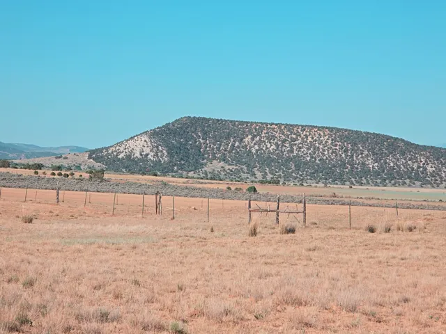 Expansive open land featuring natural fencing and a distant mountain backdrop