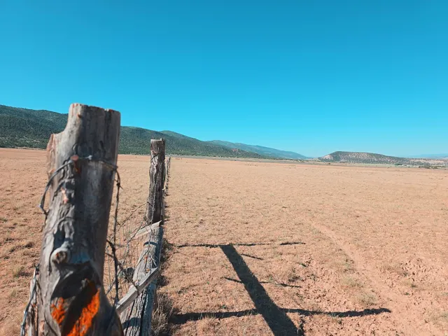 Expansive land parcel featuring natural fencing and distant mountain ranges under a clear sky