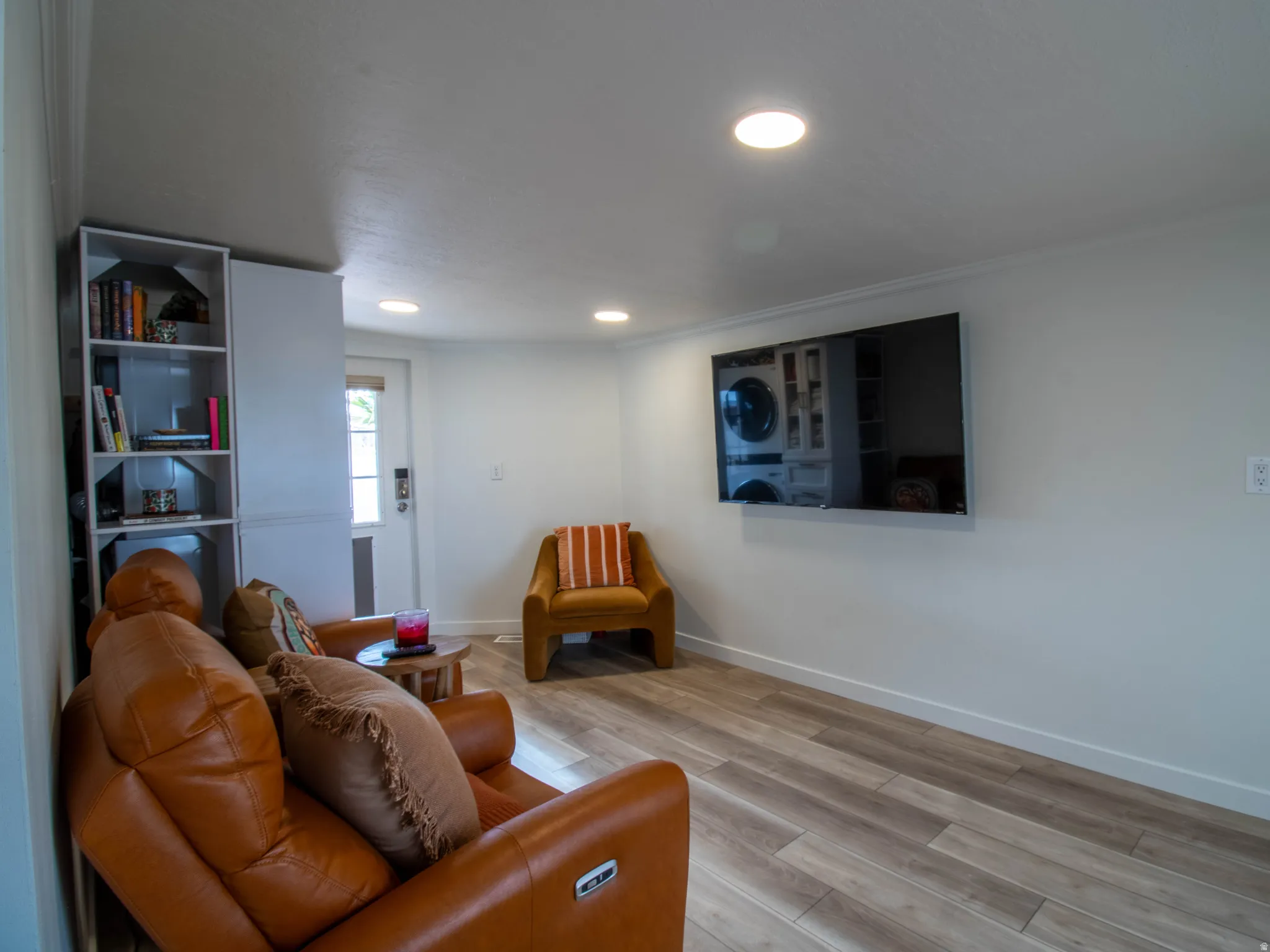 White walls with crown molding, recessed lighting, built-in shelving, wood-finish flooring, and a half-light door