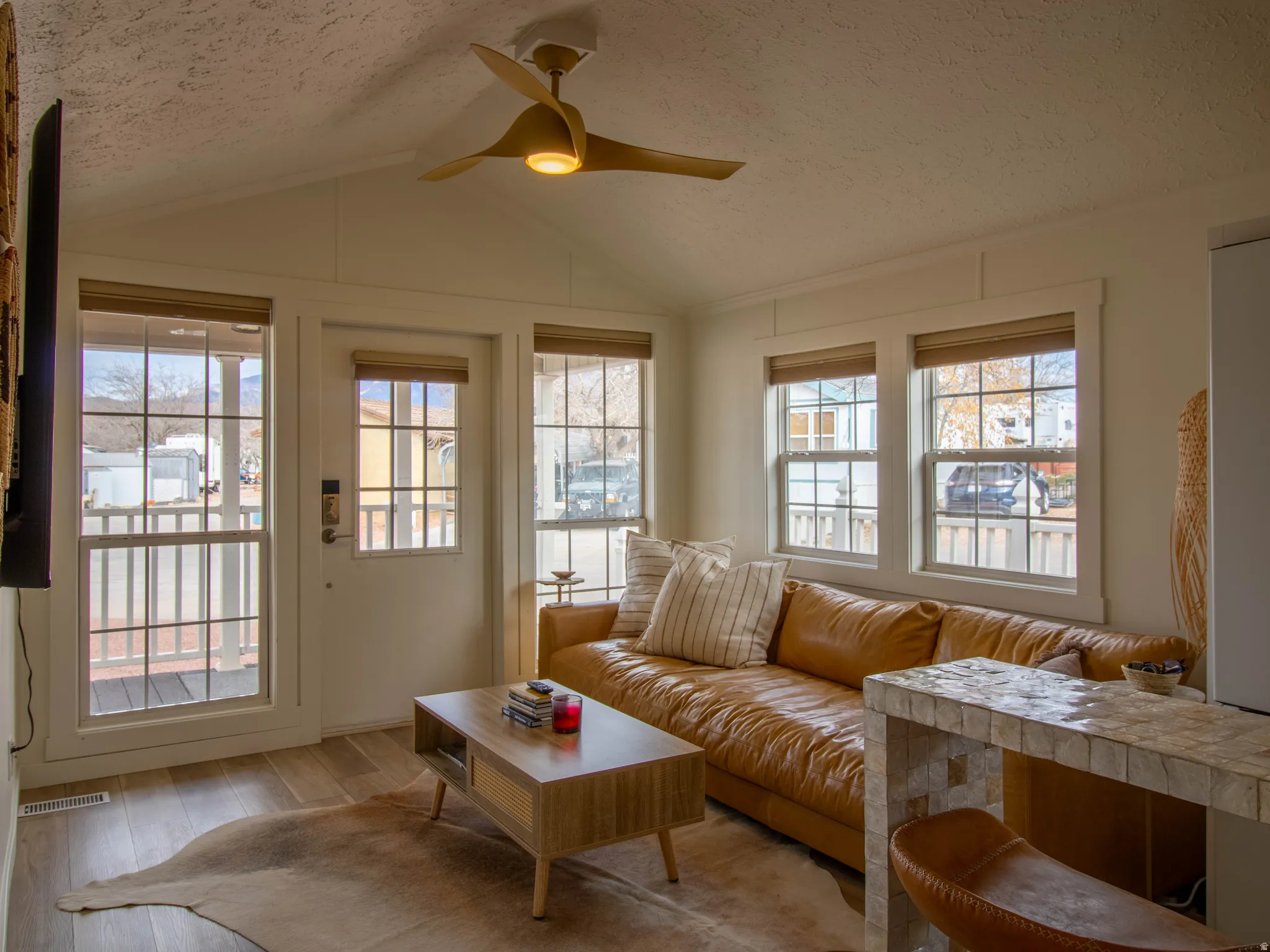 Living space featuring wood-finish flooring and a vaulted ceiling with a modern ceiling fan