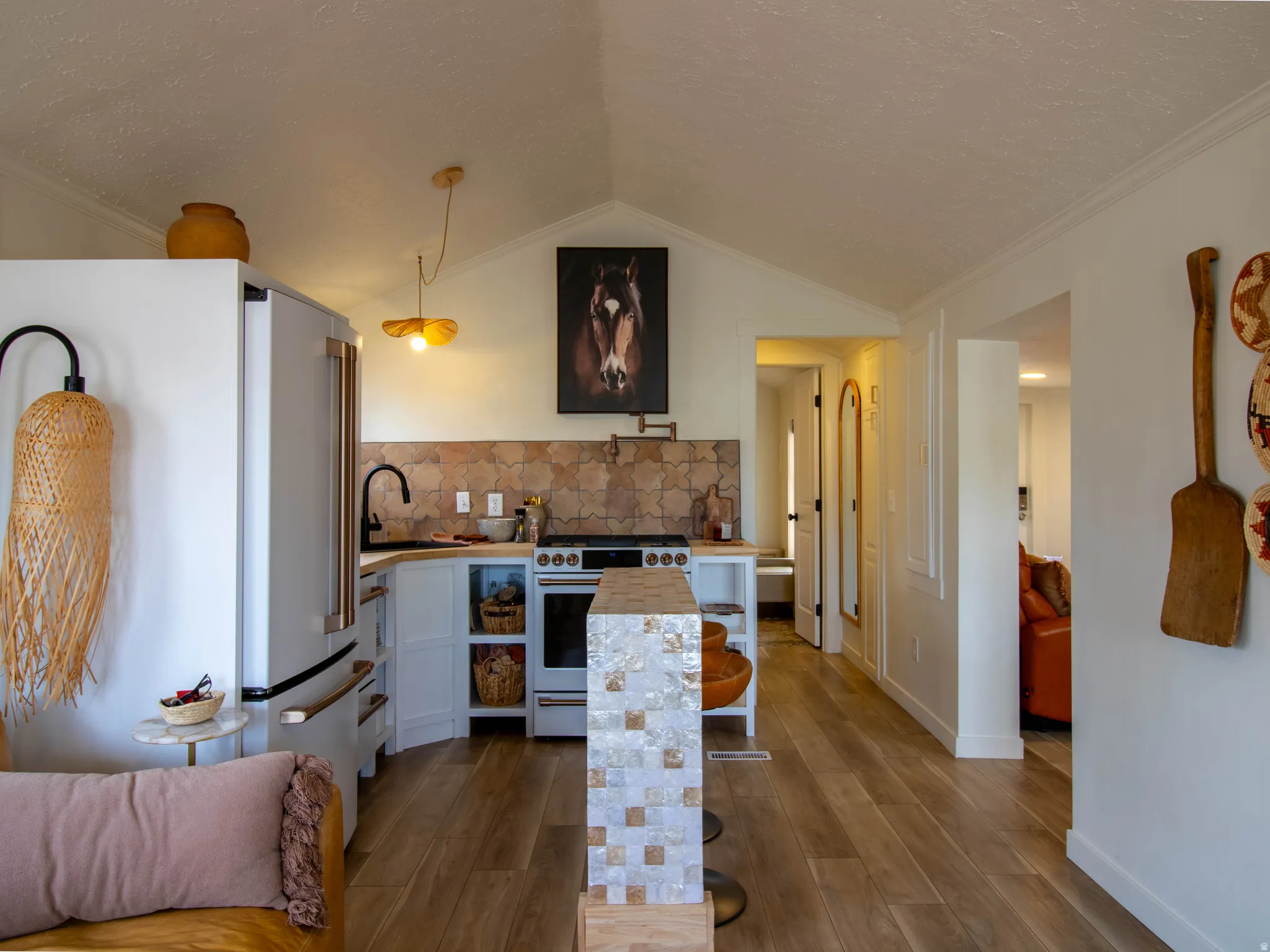 Kitchen featuring a mosaic tile backsplash, wood-finish flooring, white cabinetry, and a white refrigerator with rose gold-tone hardware