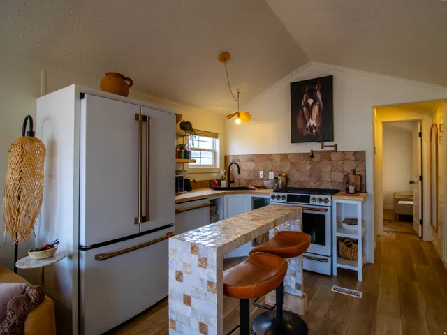 Modern kitchen featuring a mosaic-tiled breakfast bar, wood-finish flooring, and light-toned cabinetry