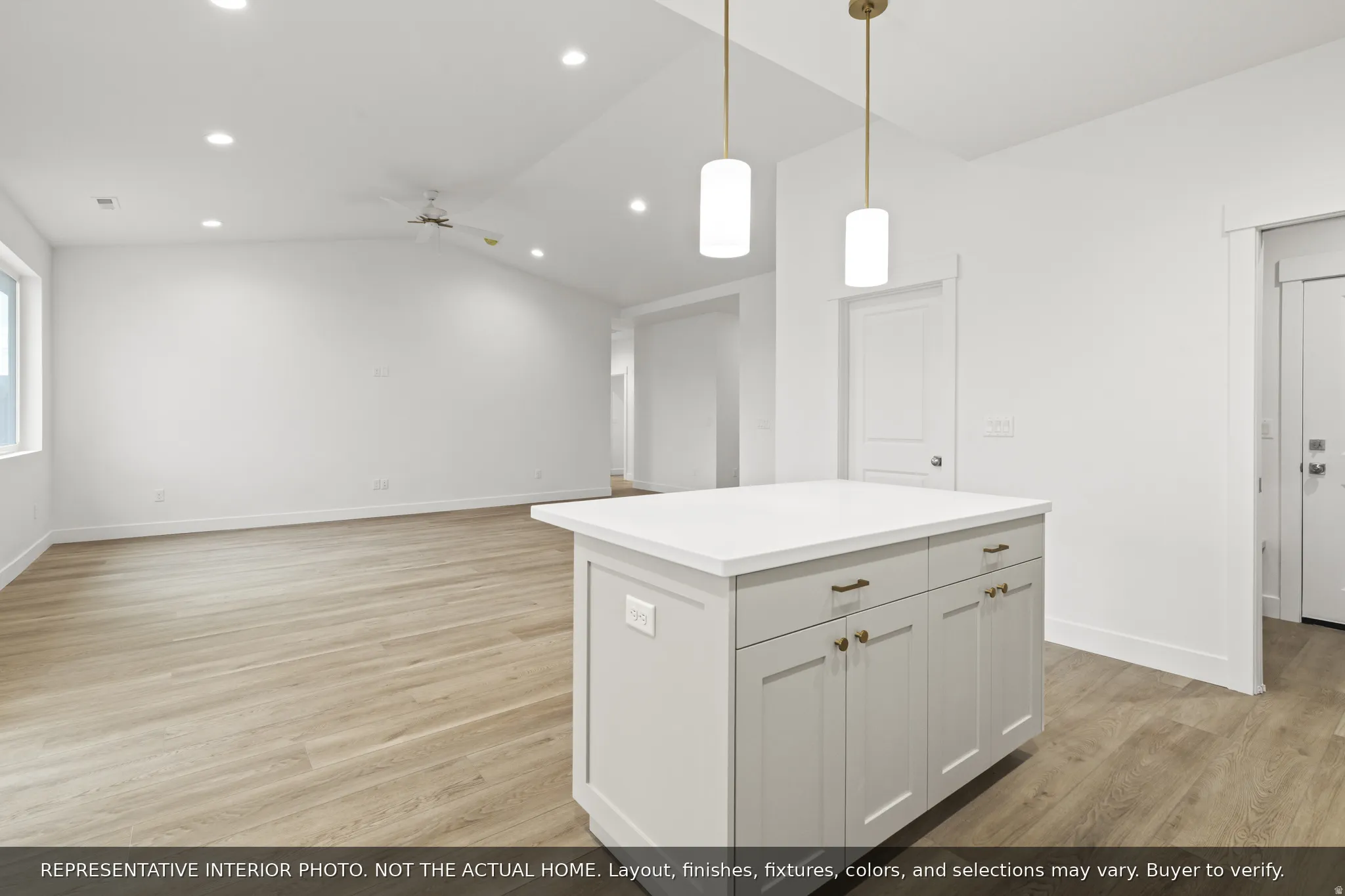Central kitchen island with a light-toned countertop, pendant lighting, and light wood-finish flooring