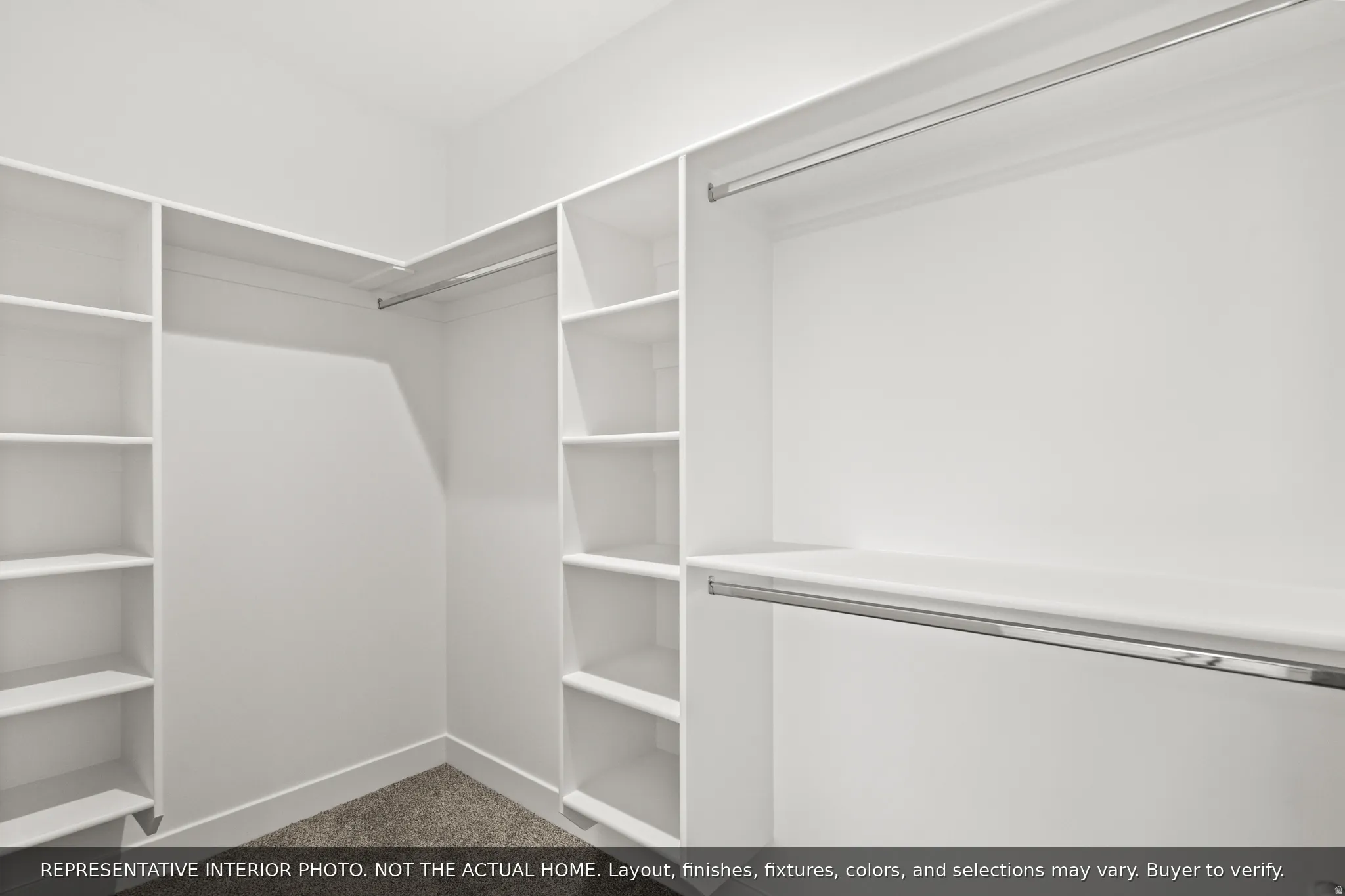 Walk-in closet featuring white built-in shelving, multiple hanging rods, and neutral-toned carpeting