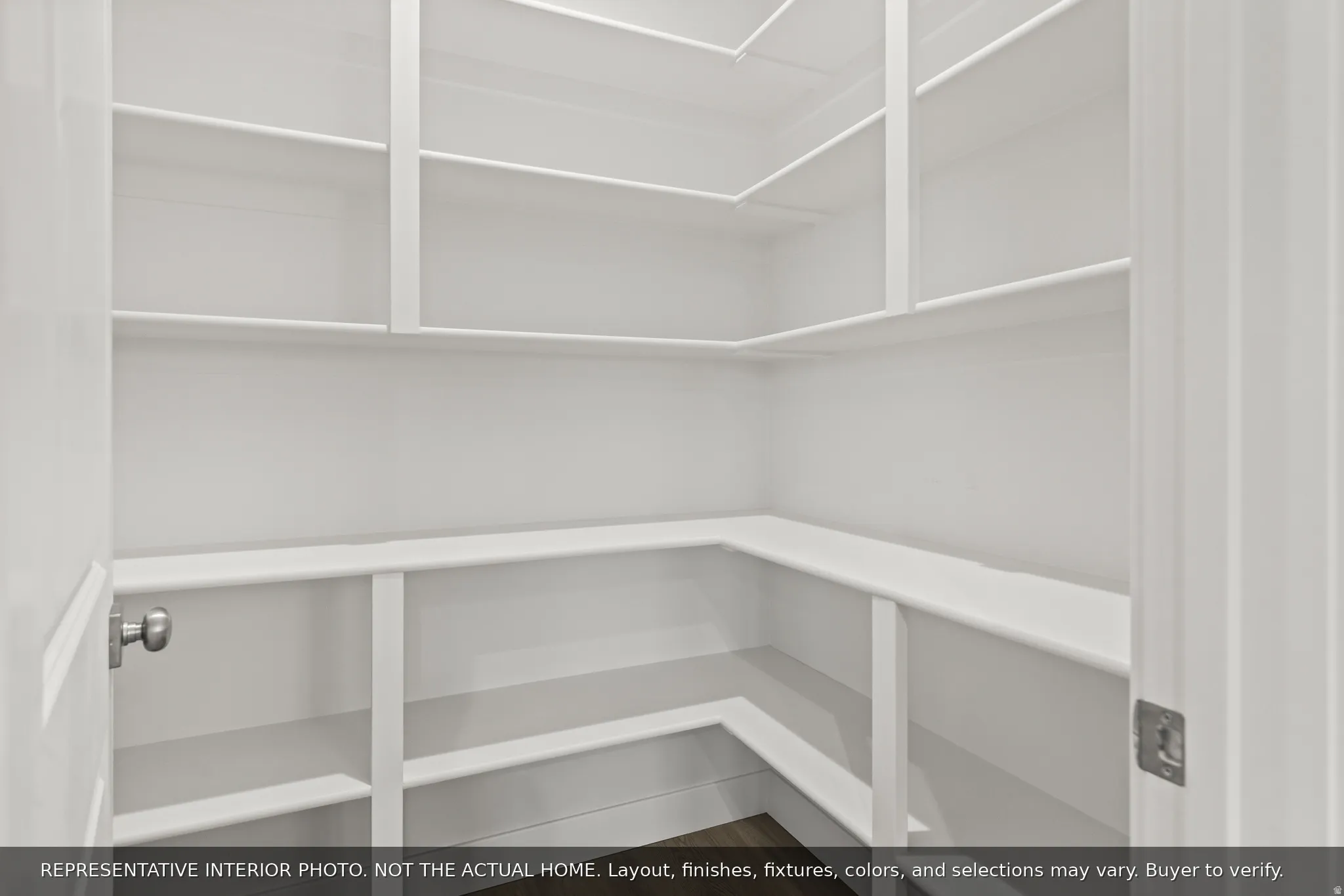 Walk-in pantry with extensive white shelving, multiple storage tiers, and wood-finish flooring