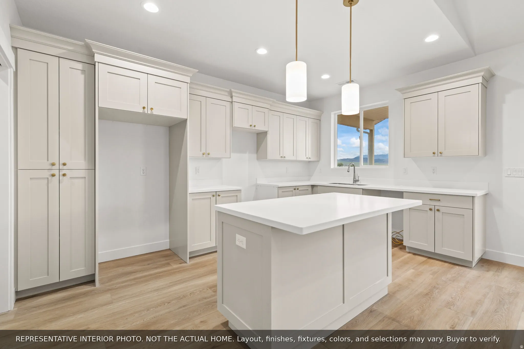 Modern kitchen featuring light-toned cabinetry, a central island with a white countertop, recessed lighting, and wood-finish flooring