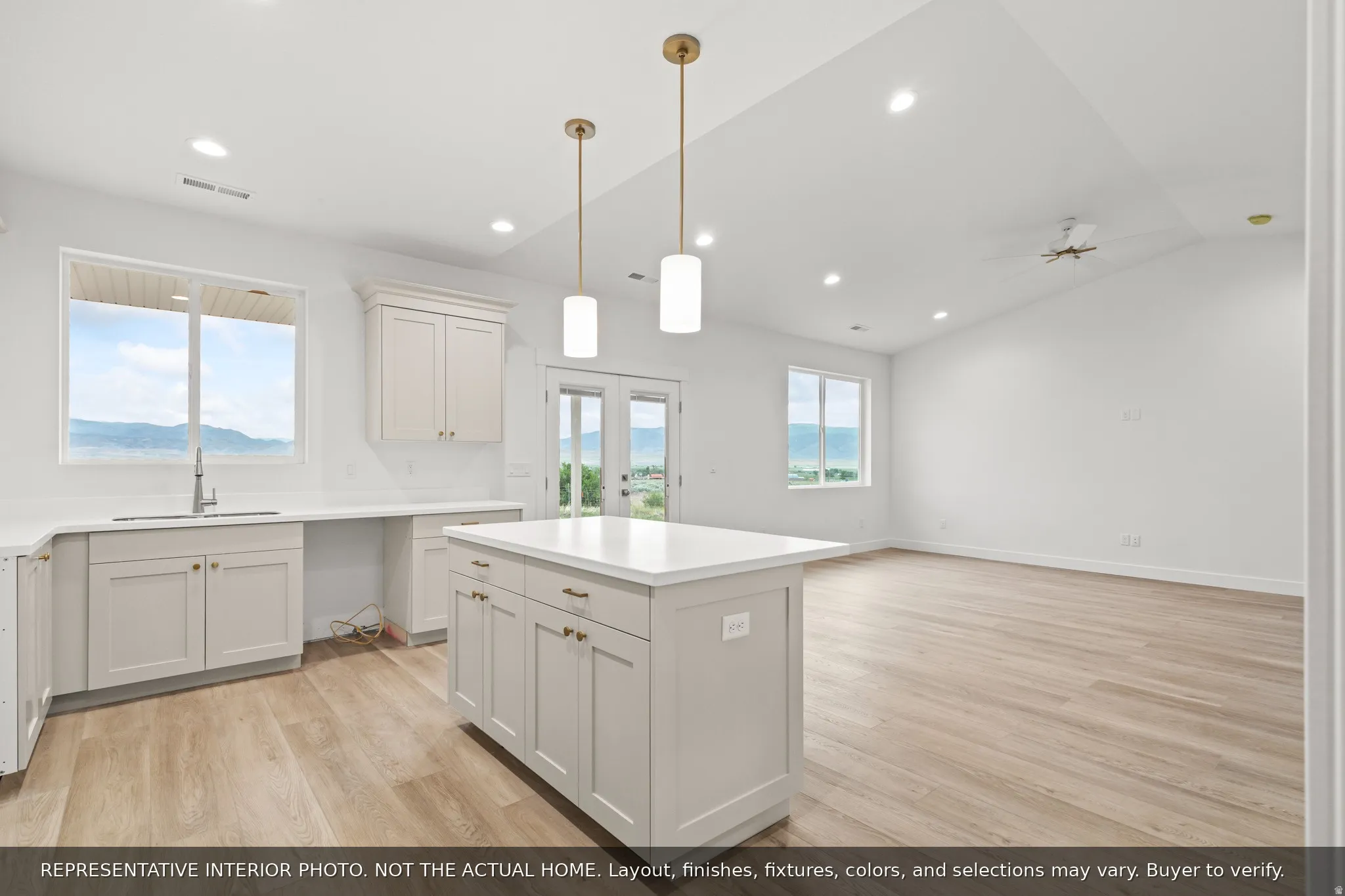 Light-filled kitchen and living area featuring a central island, recessed lighting, wood-finish flooring, white cabinetry, and dual pendant lights