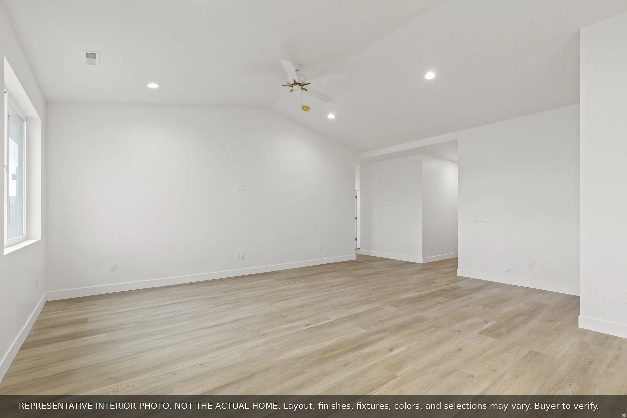 Spacious interior featuring wood-finish flooring, white walls, recessed lighting, and a ceiling fan