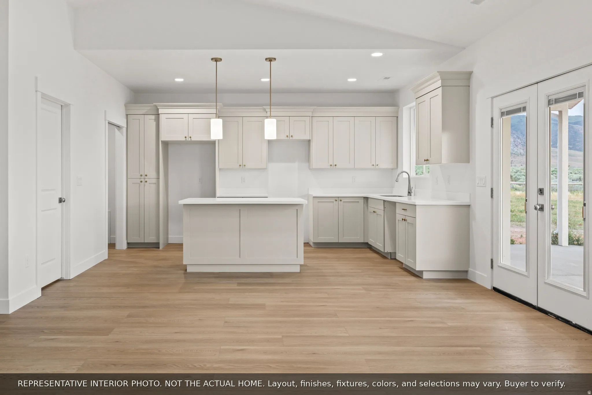 Open-concept kitchen featuring light wood-finish flooring, white cabinetry, a central island, recessed lighting, and pendant fixtures