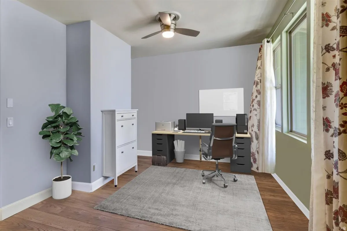 Spacious room featuring wood-finish flooring, light grey walls, and a ceiling fan with integrated lighting