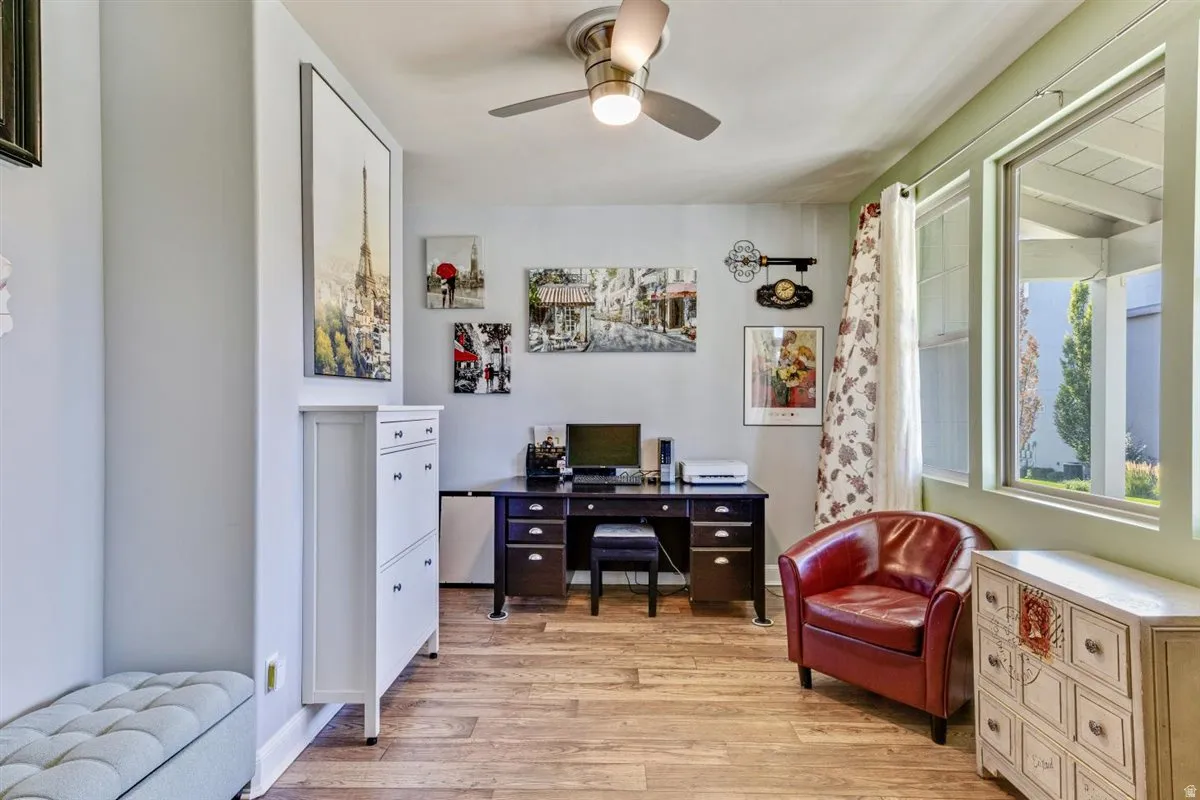 Room with wood-finish flooring, a ceiling fan, and large windows