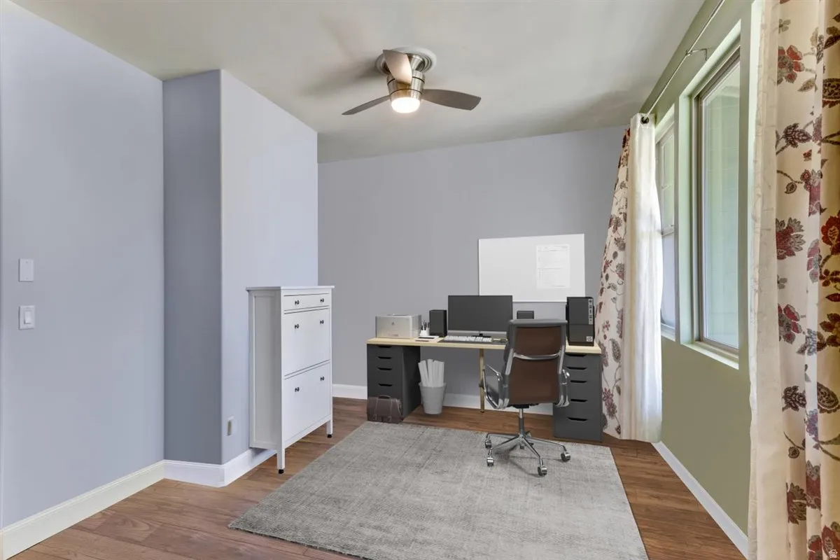 Room featuring wood-finish flooring, light grey painted walls, and a ceiling fan with integrated lighting