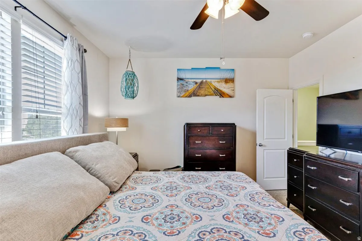 Spacious bedroom featuring light-toned walls and ample natural light from a large window with blinds