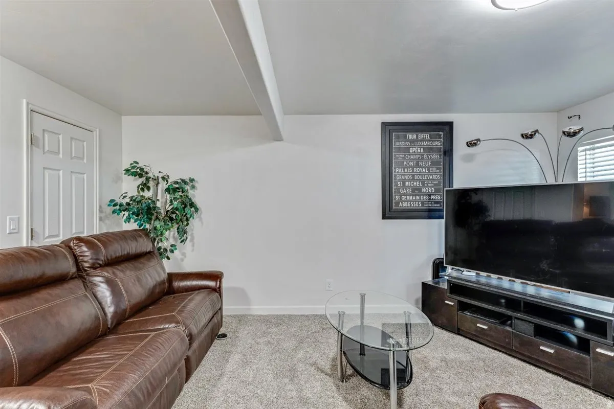 Carpeted living area featuring white walls and a white paneled door