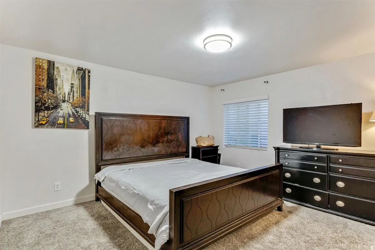 Carpeted bedroom featuring white walls and a ceiling-mounted light fixture