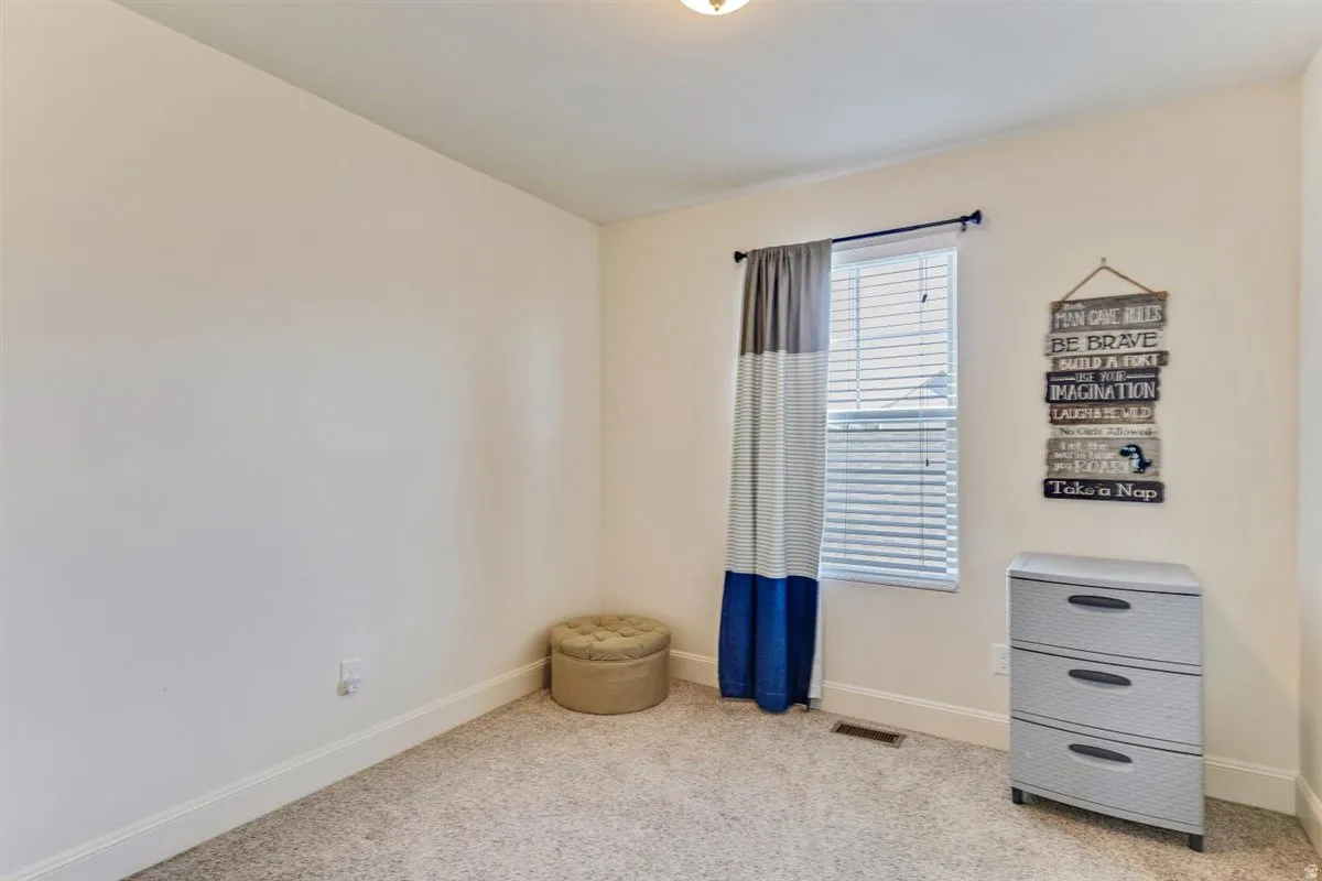 Carpeted room featuring light-toned walls, a single window with blinds, and white trim