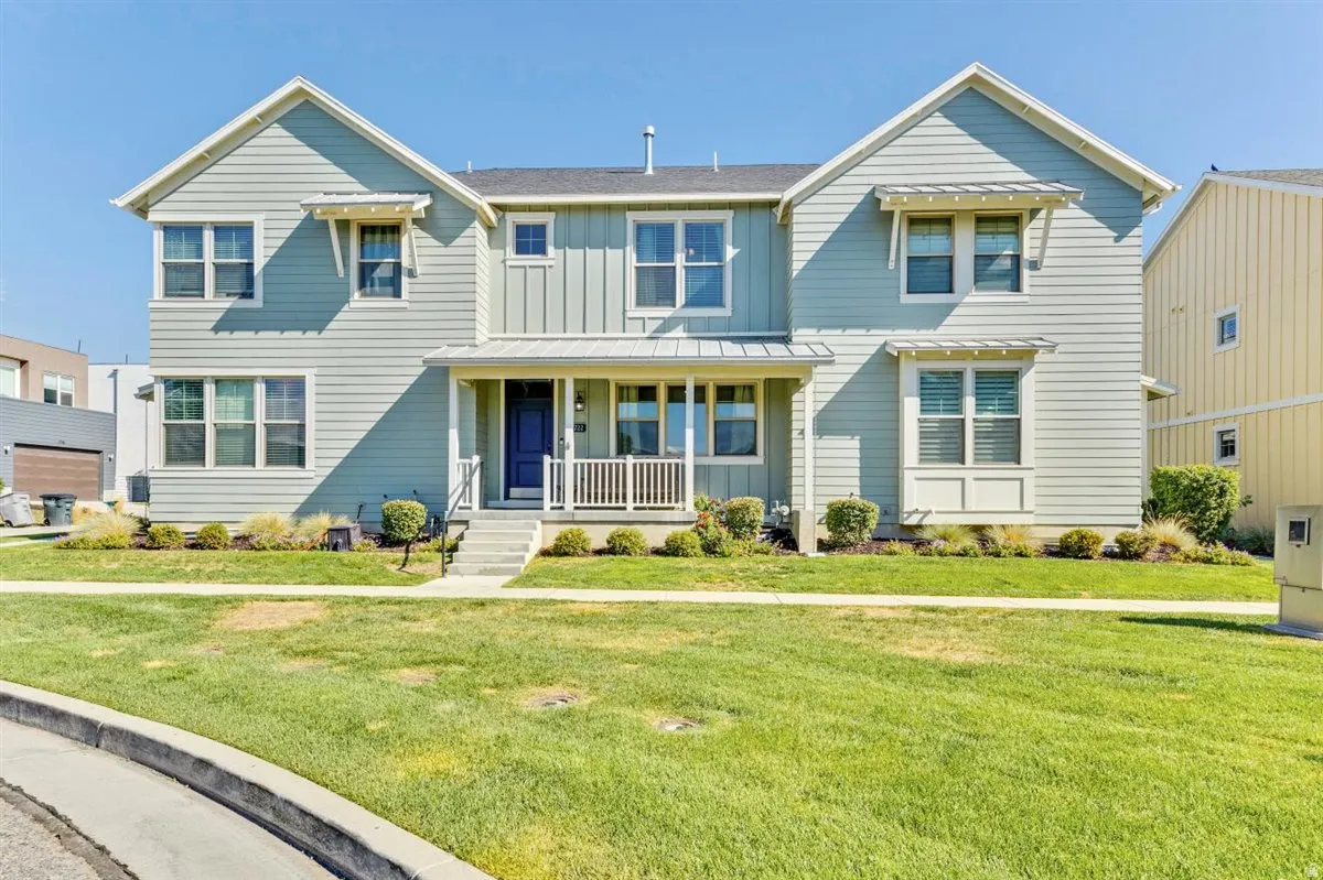 Two-story residence featuring light blue siding with white trim accents and architectural awnings