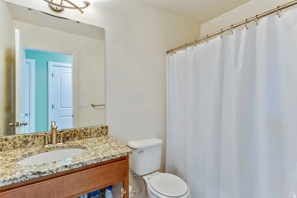 Bathroom featuring a light-toned vanity with a speckled countertop, an undermount sink, and a brushed nickel faucet