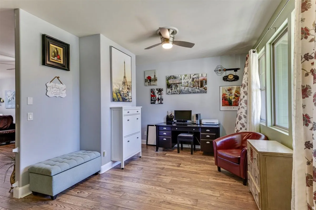 Room with wood-finish flooring, a ceiling fan, and multiple windows with vertical blinds