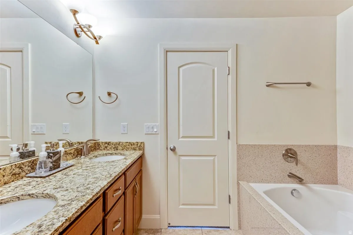 Dual vanity with granite countertop and integrated sinks, brushed nickel fixtures, and wood-finish cabinetry