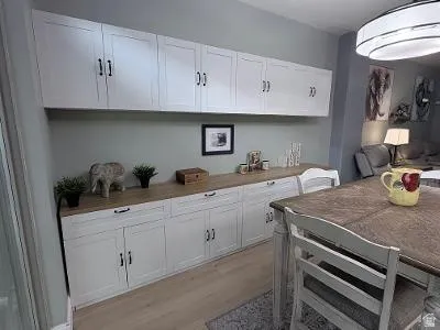 Custom built-in cabinetry featuring white shaker-style doors, black hardware, and a wood-finish countertop