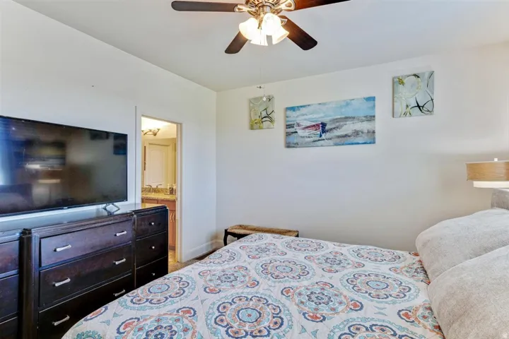 Bedroom space featuring neutral wall tones, a ceiling fan with integrated lighting, and wood-finish trim