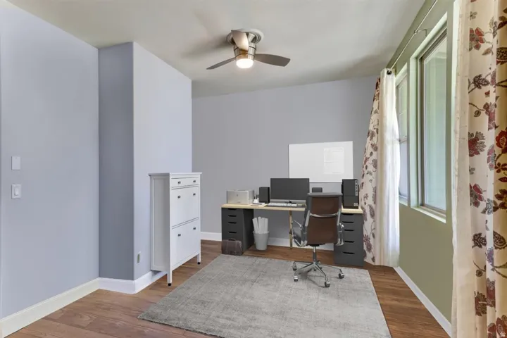 Room featuring wood-finish flooring, light grey painted walls, and a ceiling fan with integrated lighting