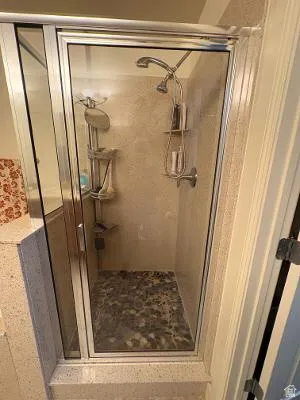 Glass-enclosed shower with a mosaic pebble floor and light-toned wall tile