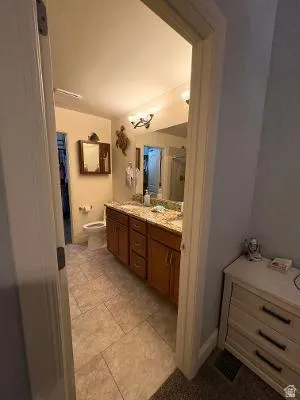 Spacious bathroom featuring an extended vanity with dual sinks, warm wood-finish cabinetry, and a light-toned countertop
