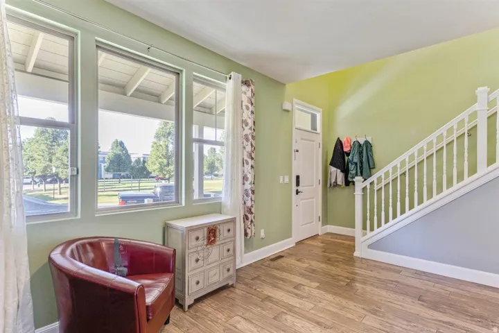 Entryway featuring wood-finish flooring, a staircase with white balusters, and a white paneled door with a transom window