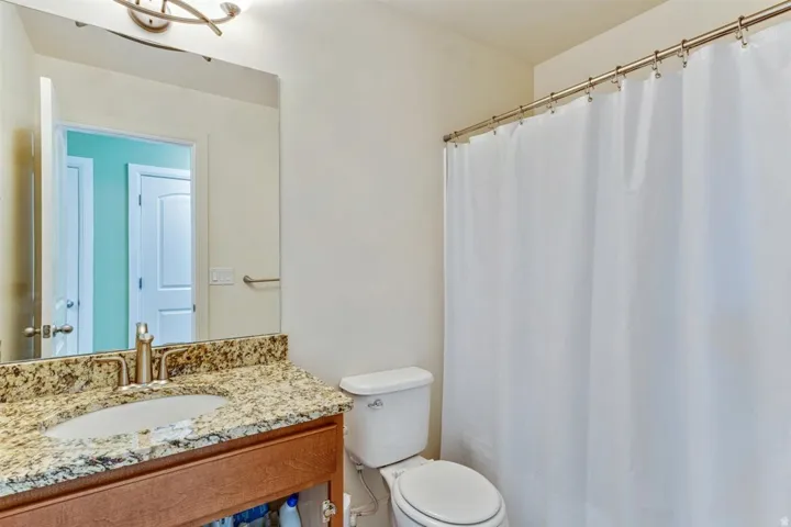 Bathroom featuring a light-toned vanity with a speckled countertop, an undermount sink, and a brushed nickel faucet