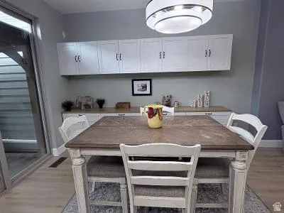 Dining area featuring a wood-finish table, overhead drum light fixture, and light wood-finish flooring