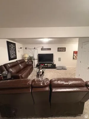 Carpeted living area featuring recessed ceiling lighting, a built-in media console, and a paneled white door