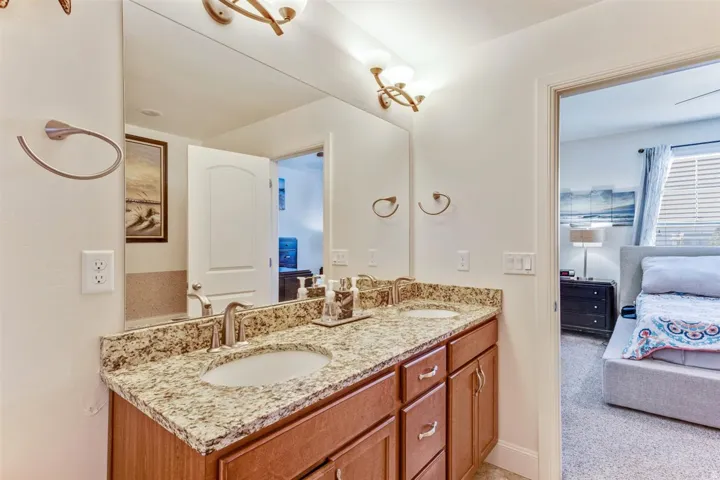 Dual vanity with stone countertop, undermount sinks, and wood cabinetry