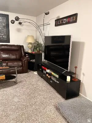 Carpeted living space featuring light-colored walls and a wall-mounted display cabinet