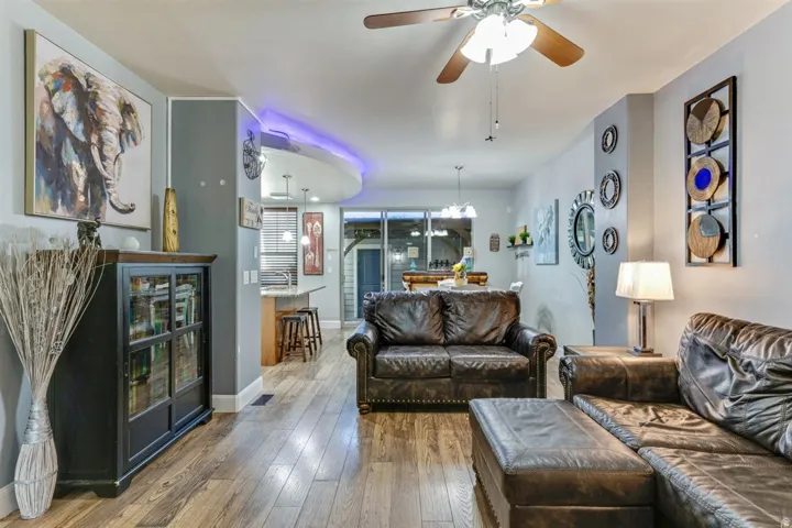 Open-concept living area with wood-finish flooring, a ceiling fan, and recessed lighting
