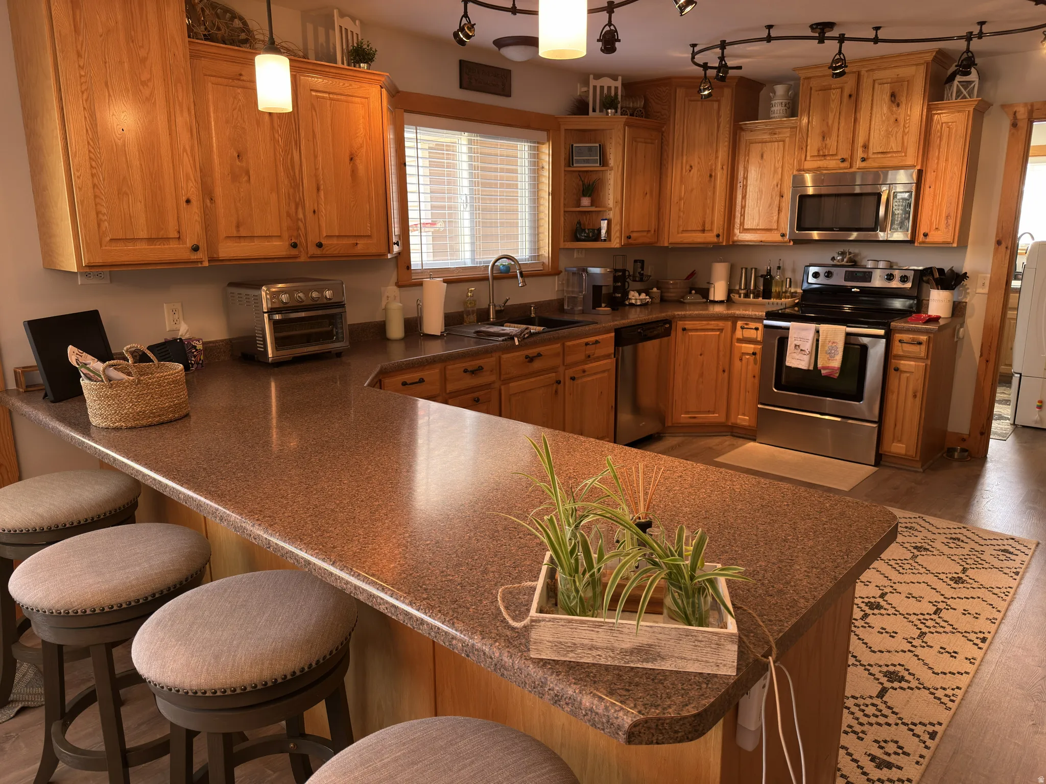 Kitchen featuring wood cabinetry, stainless steel appliances, and a peninsula with seating