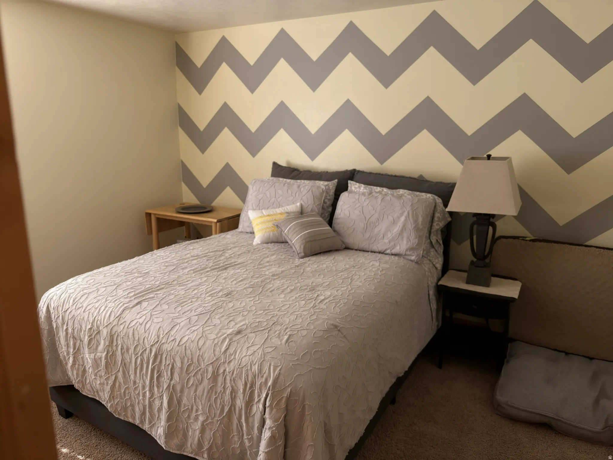 Carpeted room featuring a chevron pattern and neutral wall paint - full sized closet in room.