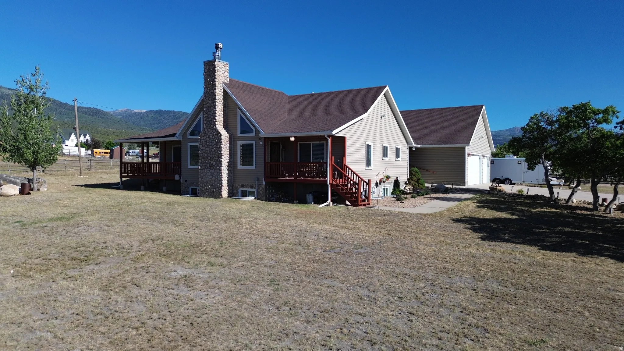 Exterior siding home featuring a stone chimney, covered porch, attached garage, and a gravel driveway