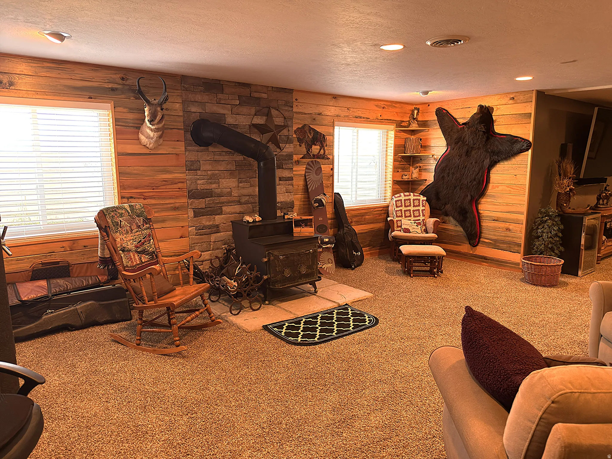 Spacious room featuring a wood-burning stove with a stone surround, wood planked walls.
