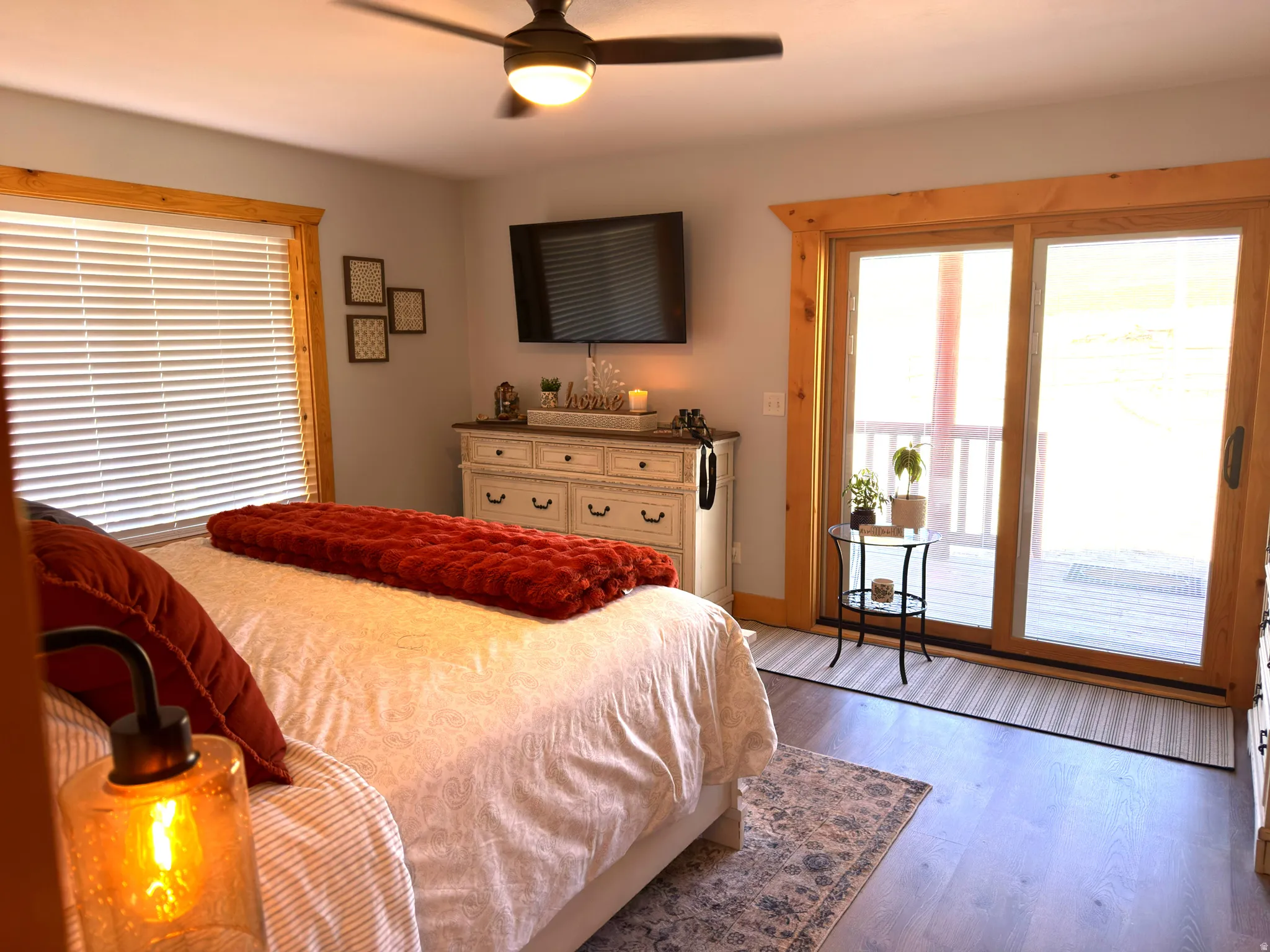 Sliding glass door with natural wood-finish trim, laminate flooring, and a ceiling fan with integrated lighting