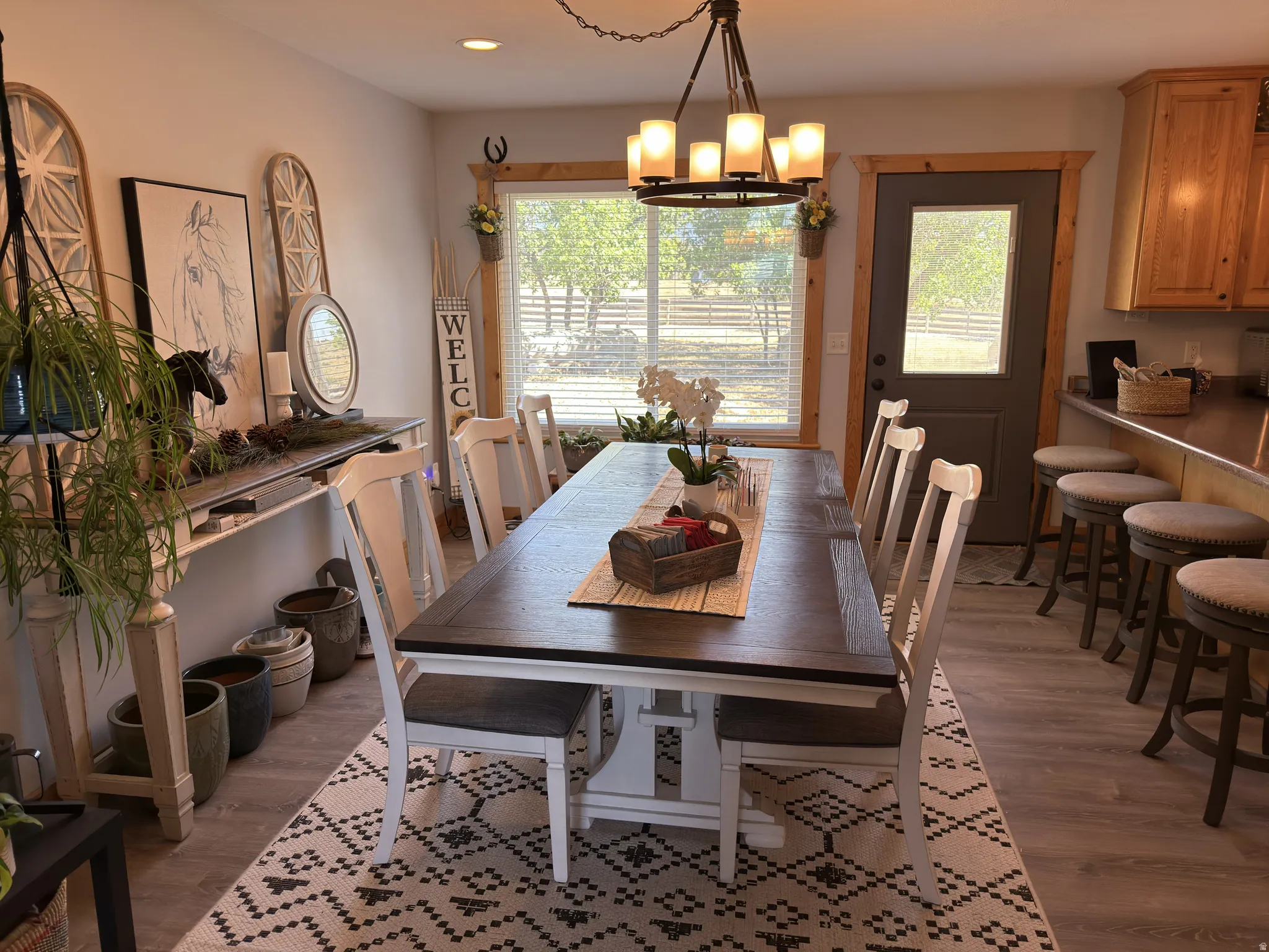 Dining area featuring laminate flooring, a multi-light chandelier, and a large picture window with natural wood trim