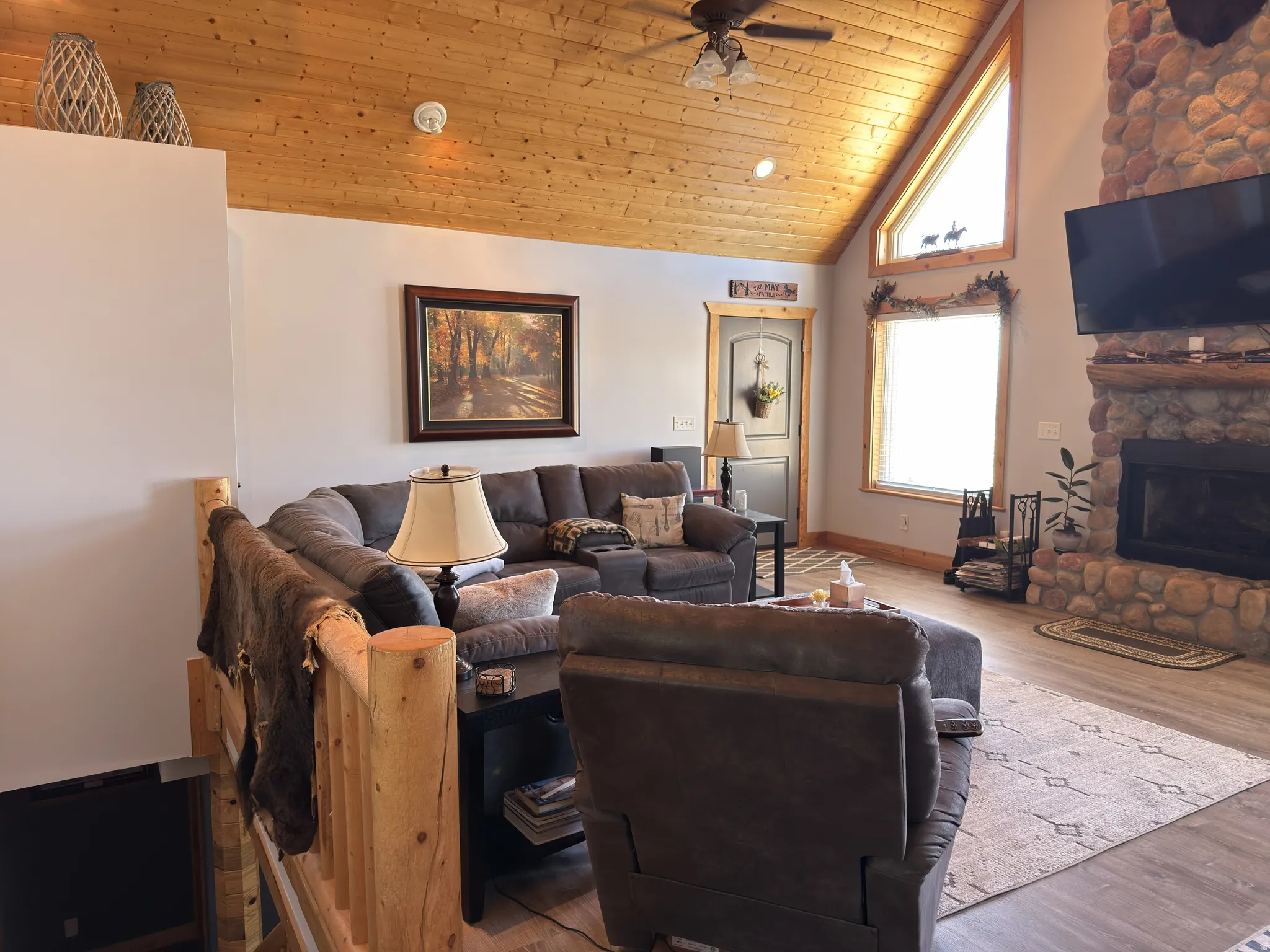Vaulted tongue and groove wood ceiling featuring dual ceiling fans with integrated lighting and laminate flooring.