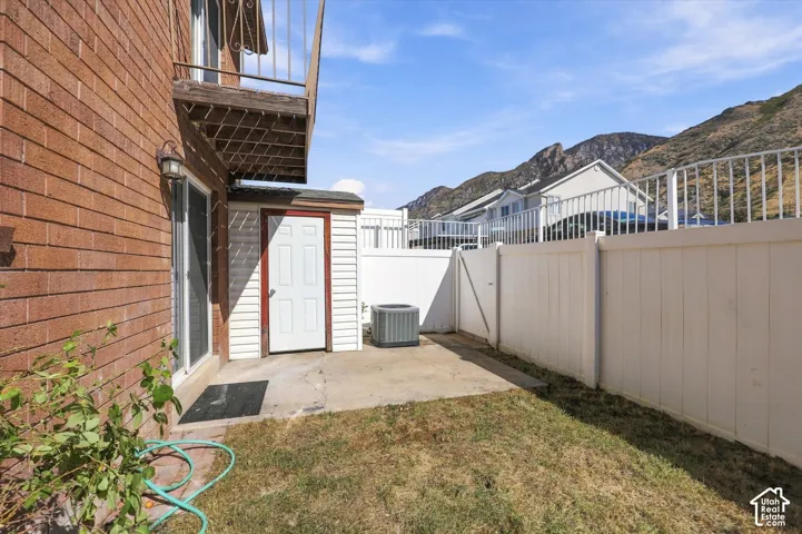 Private Backyard. Brick exterior with a second-story balcony, sliding glass door, exterior lighting, and a white privacy fence