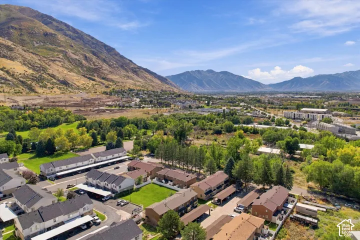 Mountain backdrop, mature trees, multi-unit properties, paved parking areas, verdant landscaping